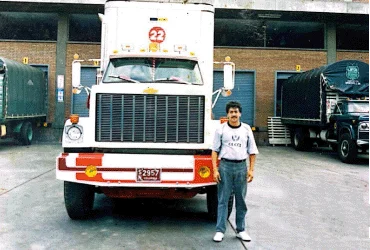Conductor frente a su tractocamión en una bodega