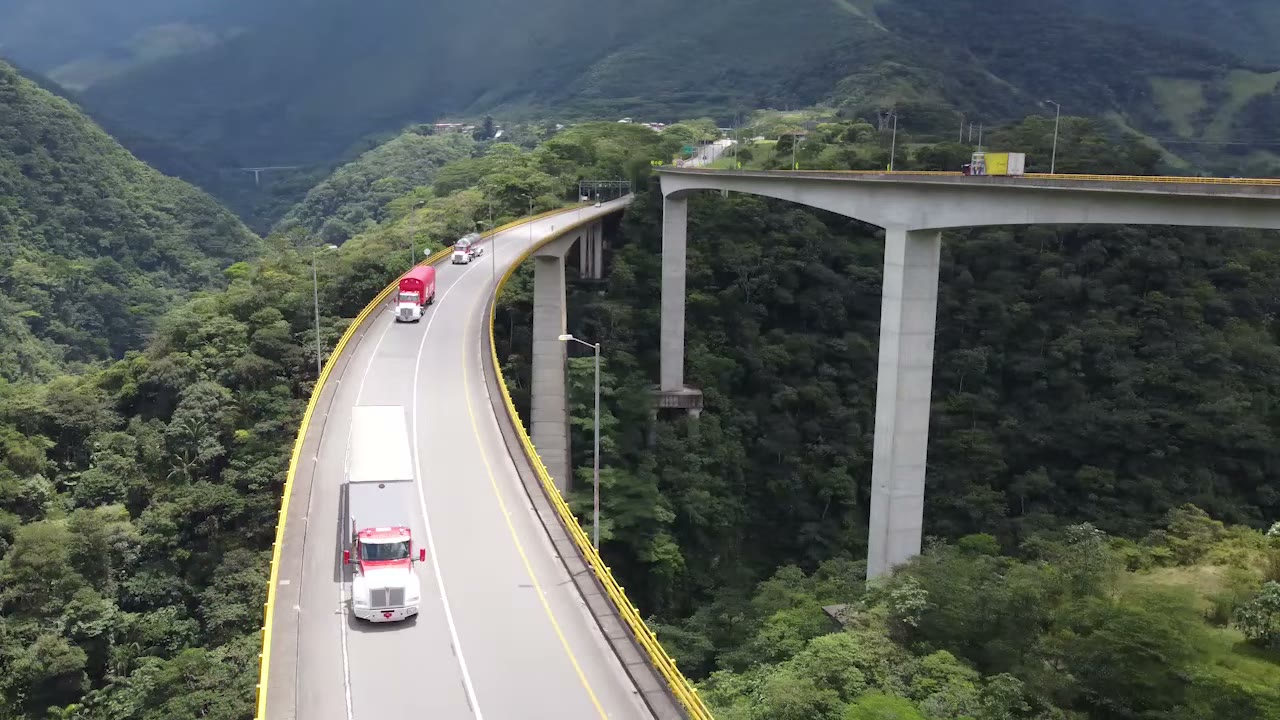 Tractocamiones de Coltanques en un viaducto curvo rodeado de montañas